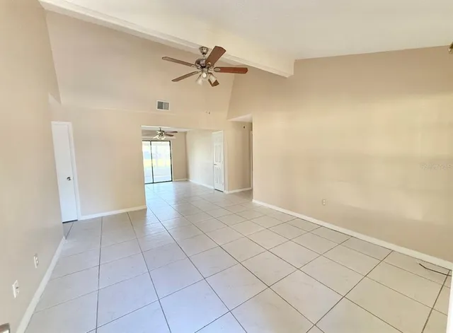 a view of an empty room and window with a chandelier fan