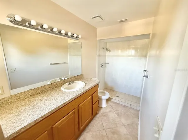 a bathroom with a granite countertop sink a mirror and a shower
