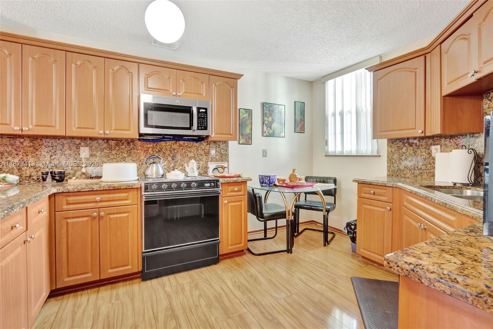 20717 Southwest 81st Place Cutler Bay, FL 33189 - Photo 6 of 23 a kitchen with stainless steel appliances granite countertop a stove top oven a sink dishwasher and white cabinets with wooden floor