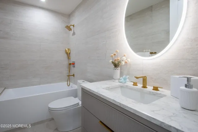 a bathroom with a granite countertop sink a toilet and bathtub