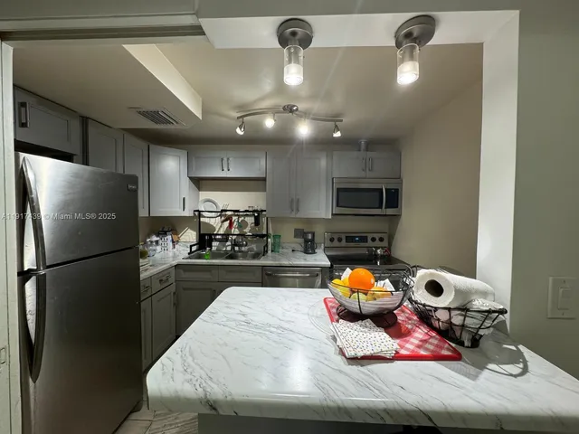 a kitchen with stainless steel appliances granite countertop a sink refrigerator and chairs