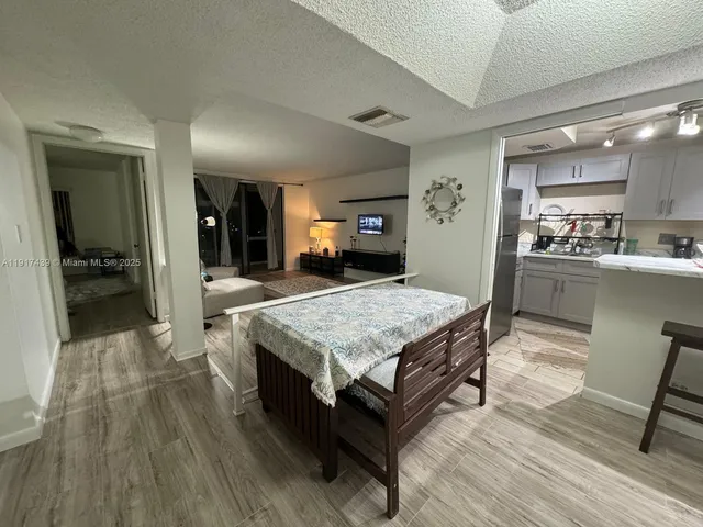 a living room with a table chairs and kitchen view