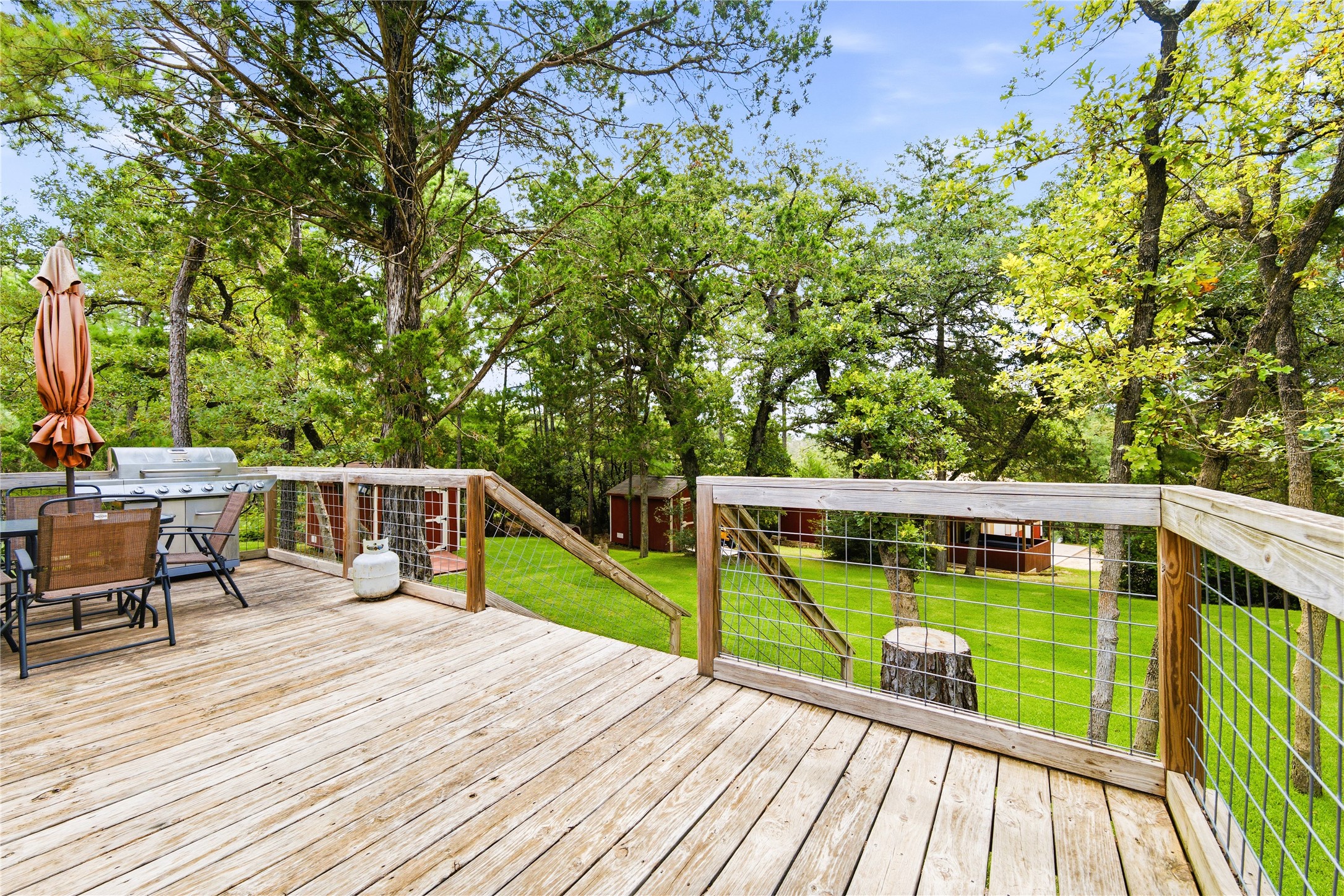 1024 Sand Hills Road Red Rock, TX 78662 - Photo 27 of 40 View of backyard featuring a spacious wooden deck provides an elevated outdoor living area overlooking a lush, tree-filled yard.