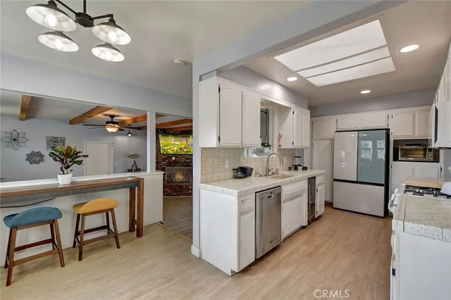 a kitchen with refrigerator a stove a sink dishwasher and cabinets with wooden floor