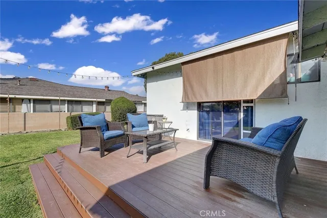 a view of a patio with couches chairs and a fire pit with wooden fence