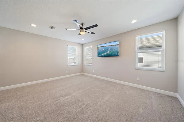 a view of an empty room and chandelier fan