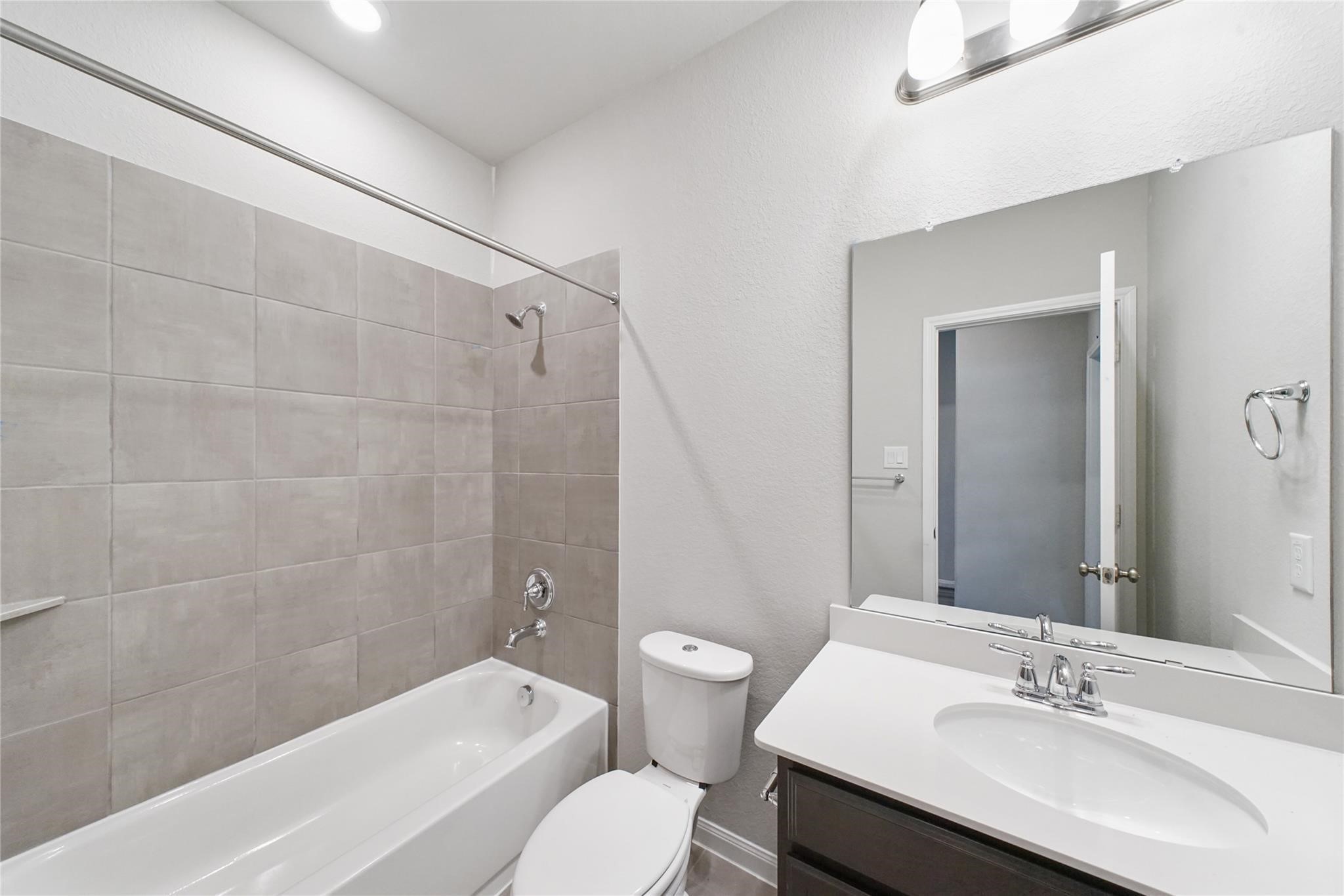 21727 Reserve Ranch Trail Richmond, TX 77407 - Photo 14 of 27 Stylish full bathroom conveniently located near the secondary main floor bedroom, featuring a sleek vanity and a tiled shower/tub combo.