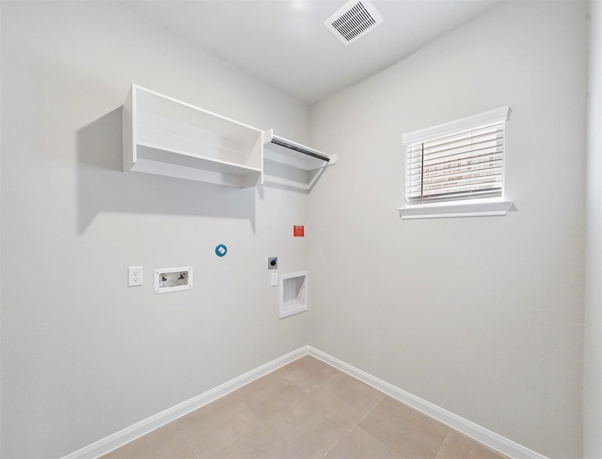 21727 Reserve Ranch Trail Richmond, TX 77407 - Photo 22 of 27 Dedicated laundry room with built-in shelving, tile flooring, and a window for natural light—functional and ready for your washer and dryer setup.