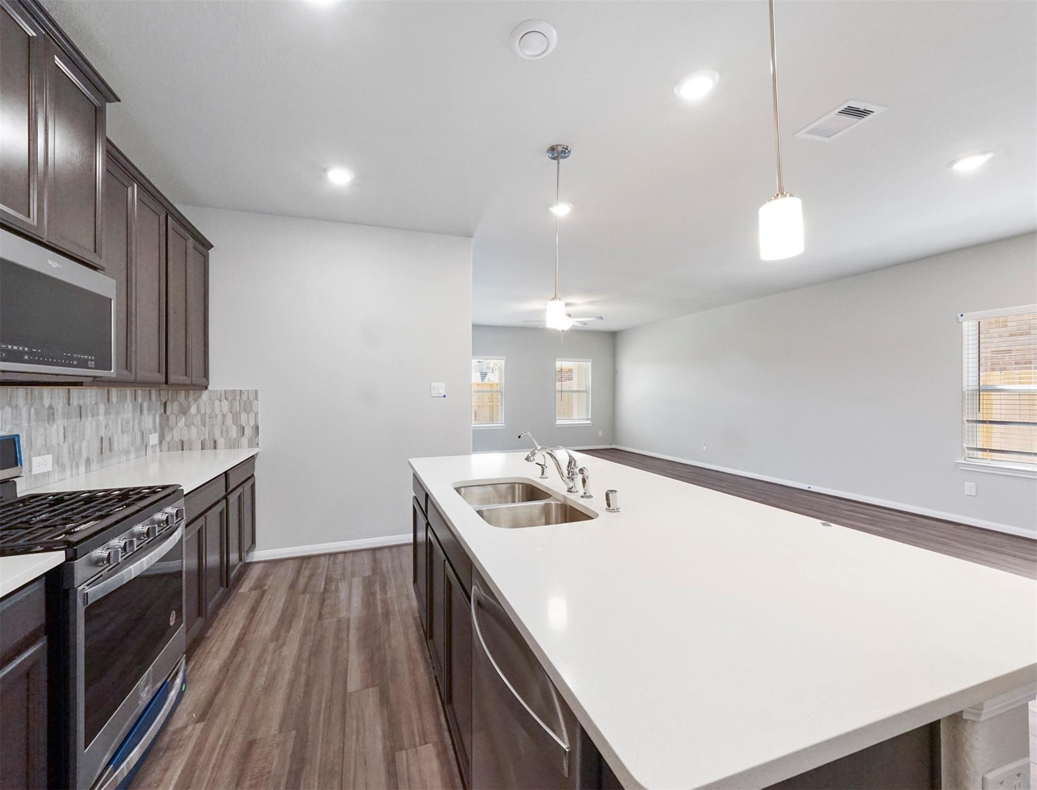 21727 Reserve Ranch Trail Richmond, TX 77407 - Photo 8 of 27 The oversized island with breakfast bar seating is the heart of this chef’s kitchen, offering ample prep space and a view into the open living area.