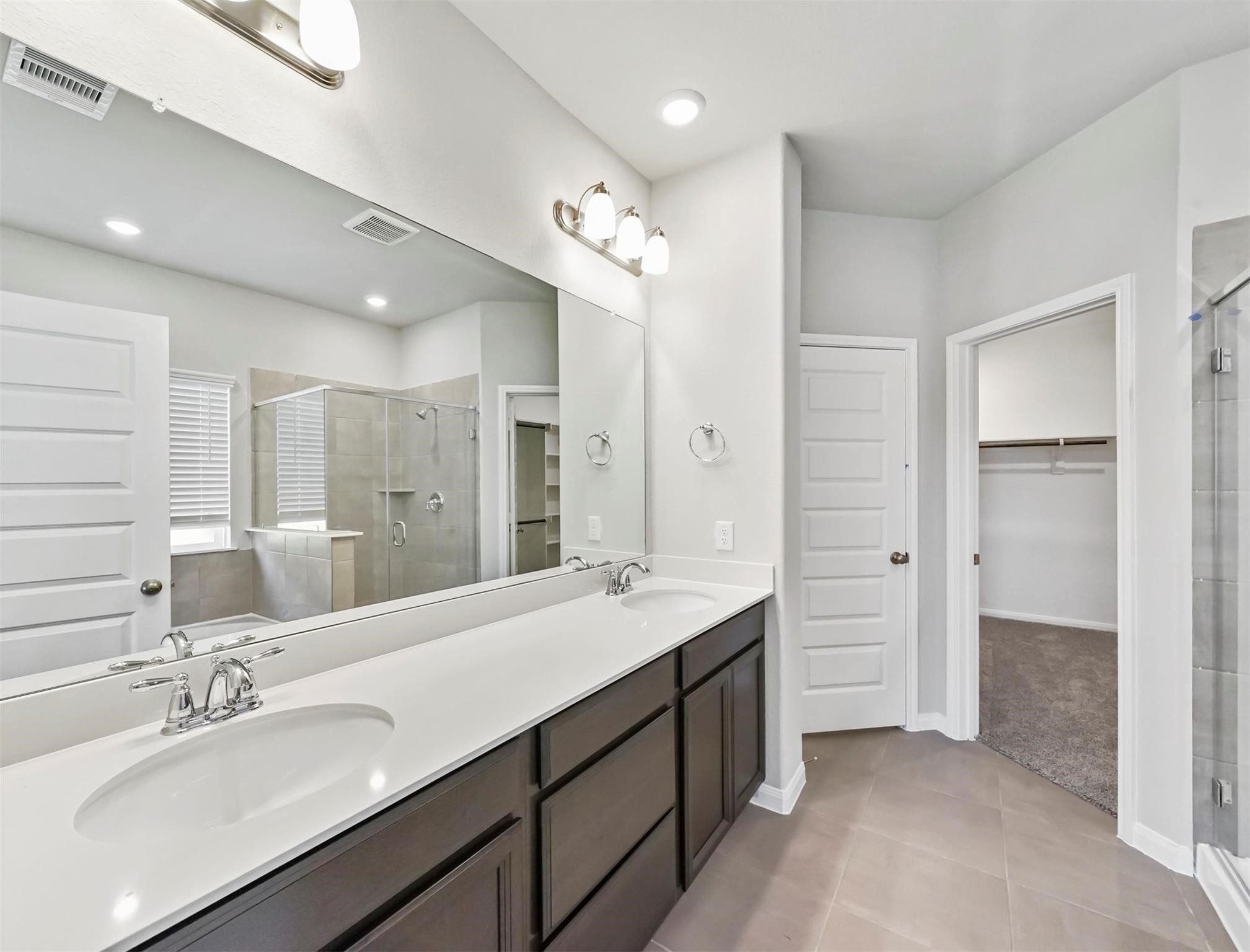 21727 Reserve Ranch Trail Richmond, TX 77407 - Photo 10 of 27 The spa-inspired primary bathroom features dual vanities, oversized mirror, and direct access to a spacious walk-in closet.
