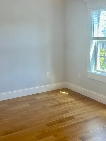 a view of an empty room with wooden floor and fan