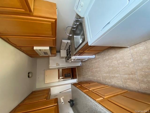 385 Grand Street, Unit L904 Manhattan, NY 10002 - Photo 5 of 6 Kitchen with washer / clothes dryer, white gas range oven, brown cabinetry, and stainless steel microwave