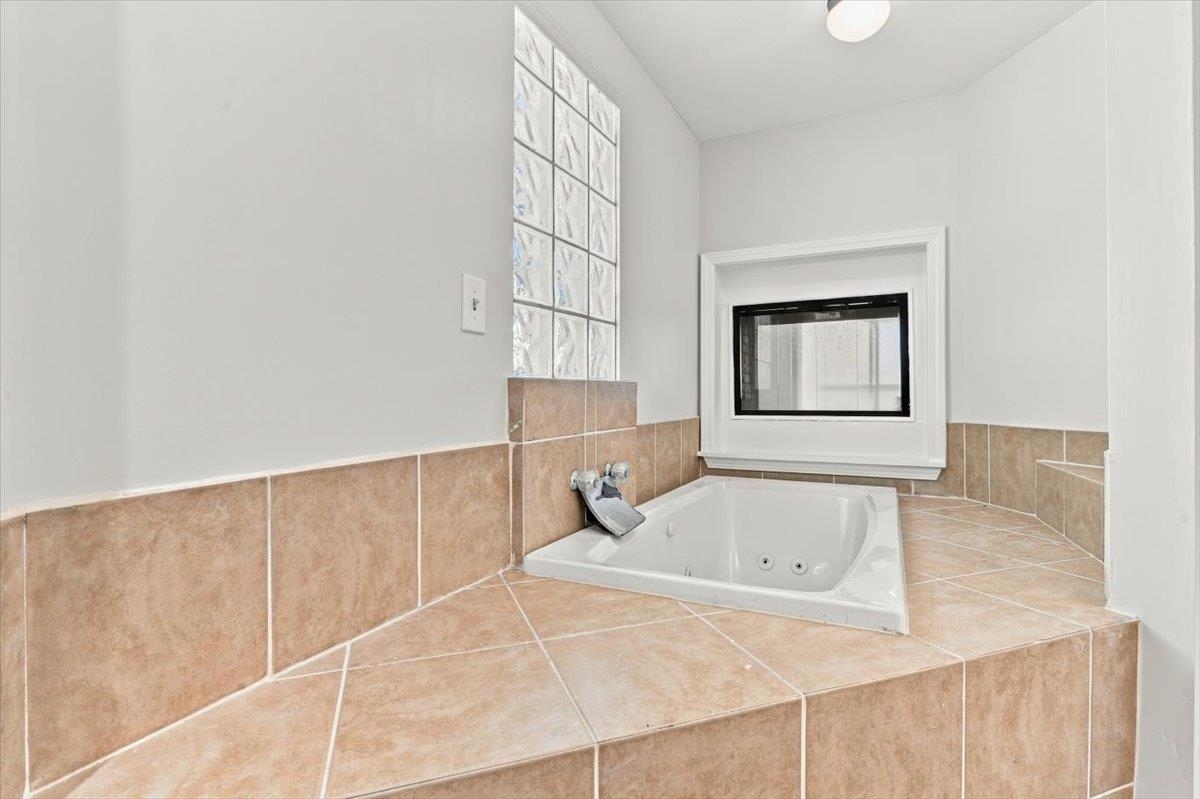 655 Riverside Drive, Unit 608B Memphis, TN 38103 - Photo 20 of 28 Jetted tub with tile surround, glass block window, and built-in fireplace feature