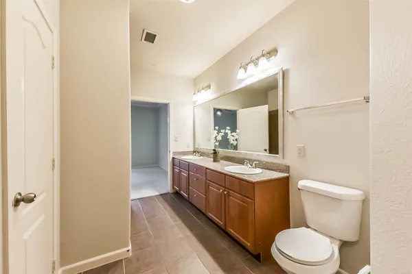 a bathroom with a granite countertop toilet sink and mirror