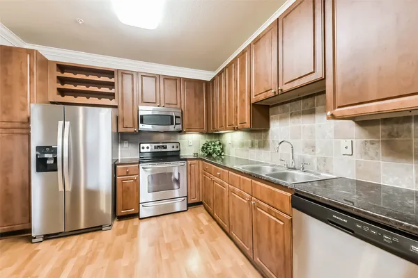 a kitchen with granite countertop a refrigerator stove and sink