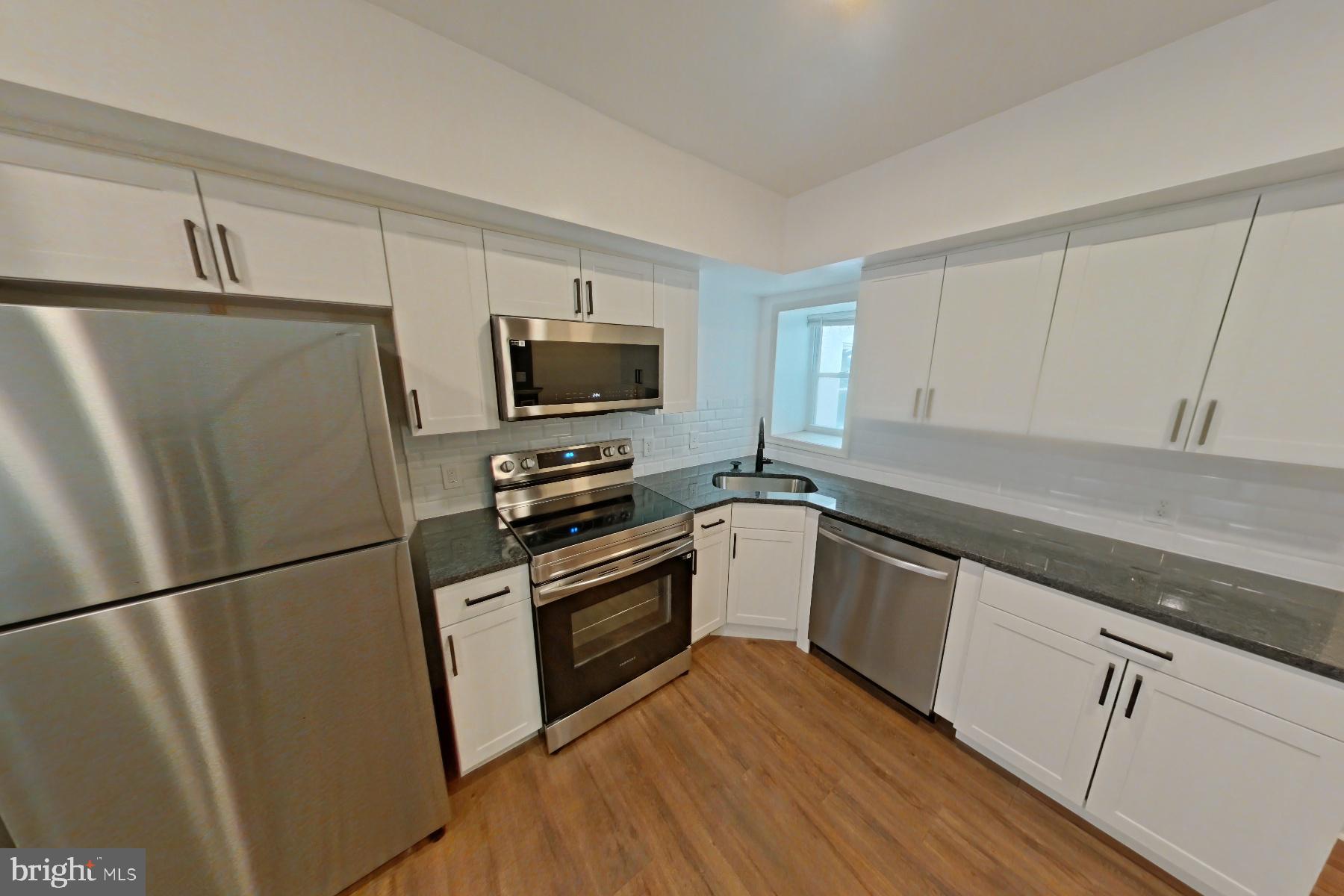 a kitchen with granite countertop a refrigerator stove and microwave