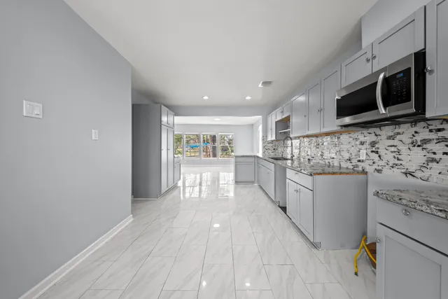 a large kitchen with stainless steel appliances granite countertop a stove sink and cabinets