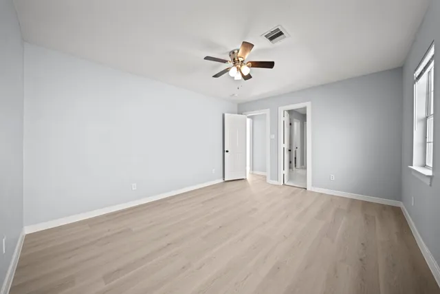 a view of an empty room with a window and wooden floor