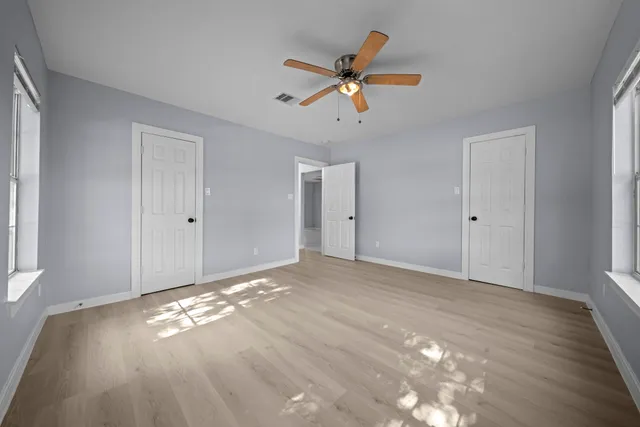a view of empty room with wooden floor and fan