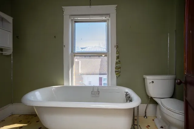 an empty room with wooden floor cabinet and windows
