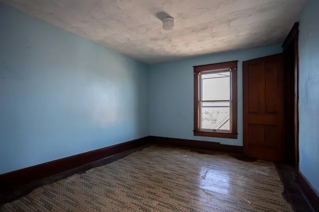 a view of an empty room with wooden floor and closet