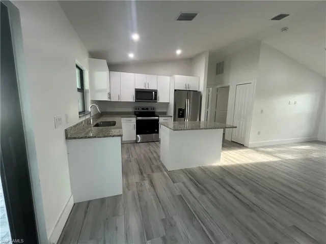 a kitchen with stainless steel appliances granite countertop a refrigerator stove top oven and sink