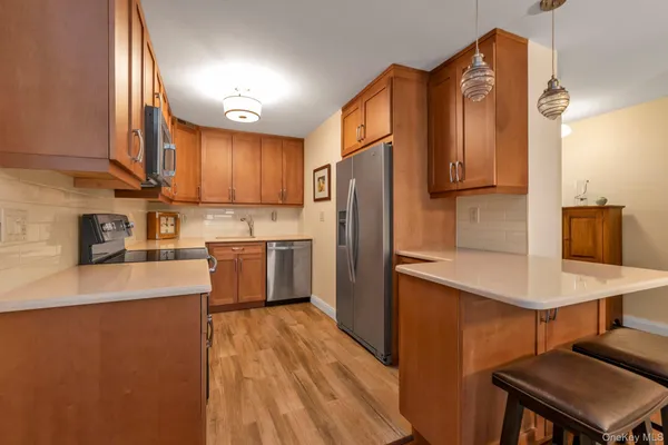 a kitchen with stainless steel appliances granite countertop a refrigerator a sink dishwasher a stove with wooden floor and cabinets