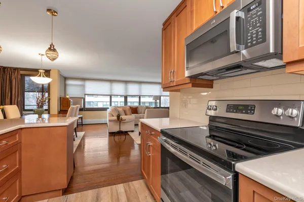 a open kitchen with stainless steel appliances granite countertop a stove top oven a dining table and chairs with wooden floor