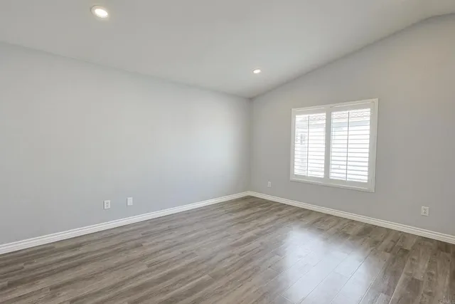 a view of an empty room with wooden floor and window