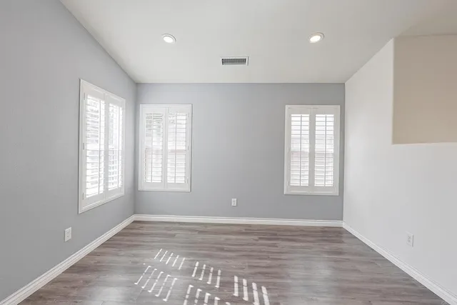 a view of an empty room with a window and wooden floor
