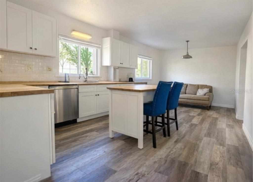 445 State Rte 415 Osteen, FL 32764 - Photo 9 of 25 a kitchen with granite countertop wooden floors and white cabinets