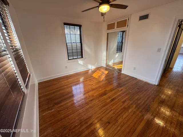 an empty room with wooden floor and windows