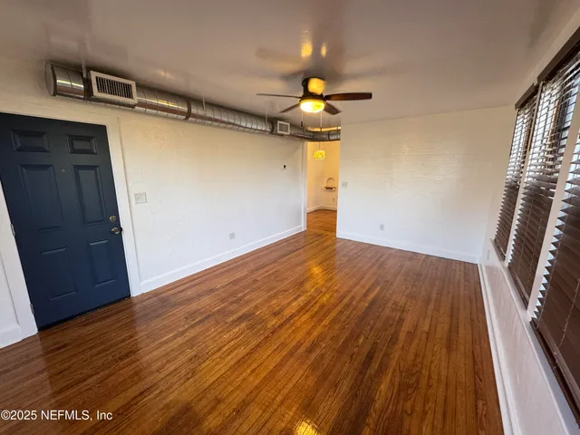 a view of empty room with wooden floor