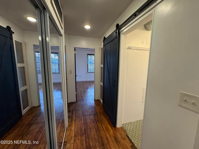 a view of hallway with stainless steel appliances a refrigerator and wooden floor