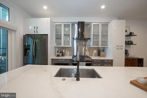 a kitchen with kitchen island a counter top space a sink stainless steel appliances and cabinets