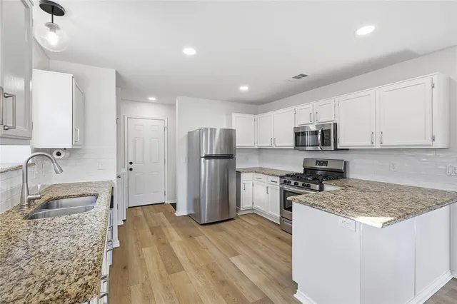 a kitchen with stainless steel appliances granite countertop a sink stove and refrigerator