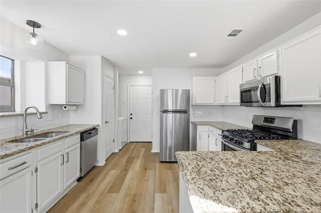 a kitchen with stainless steel appliances granite countertop a refrigerator stove microwave and sink