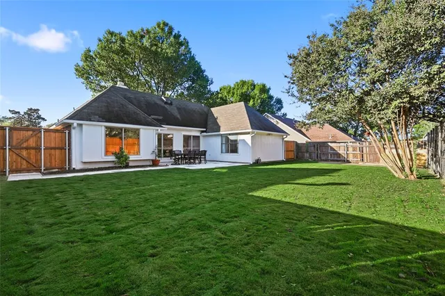 a view of a white house in front of a big yard with large trees