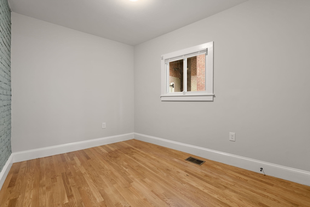 129 Sutherland Road, Unit A Boston, MA 02135 - Photo 11 of 38 a view of an empty room with wooden floor and a window