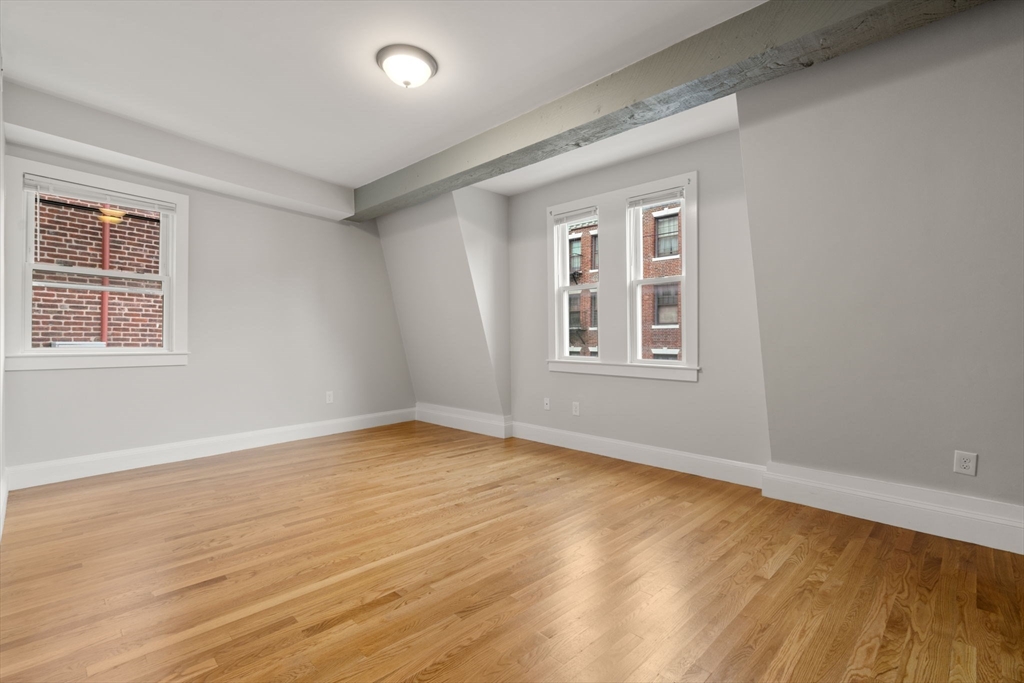 129 Sutherland Road, Unit A Boston, MA 02135 - Photo 13 of 38 a view of an empty room with wooden floor and a window