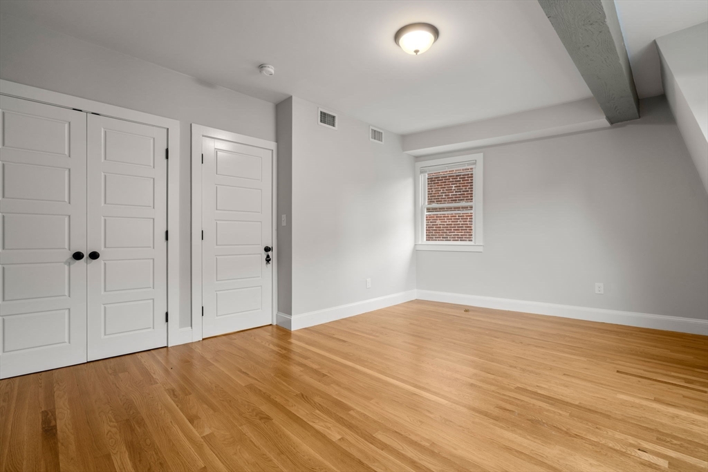 129 Sutherland Road, Unit A Boston, MA 02135 - Photo 14 of 38 an empty room with wooden floor and windows