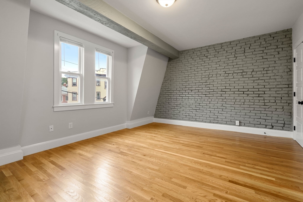 129 Sutherland Road, Unit A Boston, MA 02135 - Photo 16 of 38 a view of an empty room with wooden floor and a window