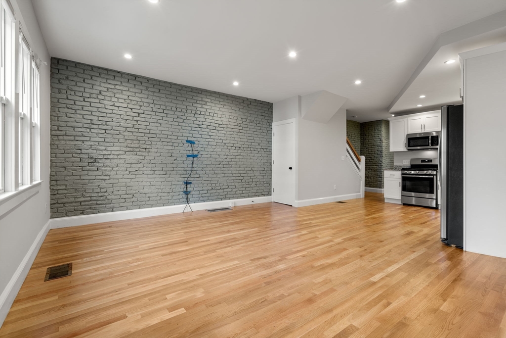 129 Sutherland Road, Unit A Boston, MA 02135 - Photo 2 of 38 a view of empty room with wooden floor and windows