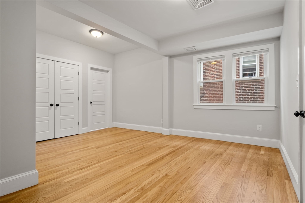 129 Sutherland Road, Unit A Boston, MA 02135 - Photo 21 of 38 a view of an empty room with wooden floor and a window