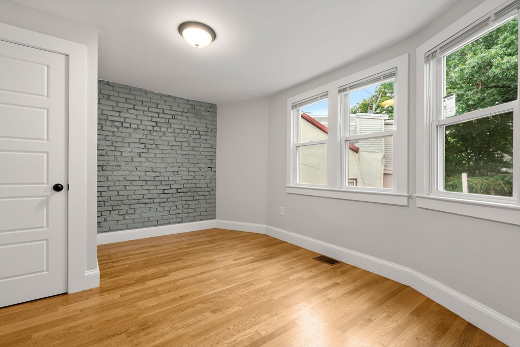 129 Sutherland Road, Unit A Boston, MA 02135 - Photo 25 of 38 a view of an empty room with wooden floor and a window