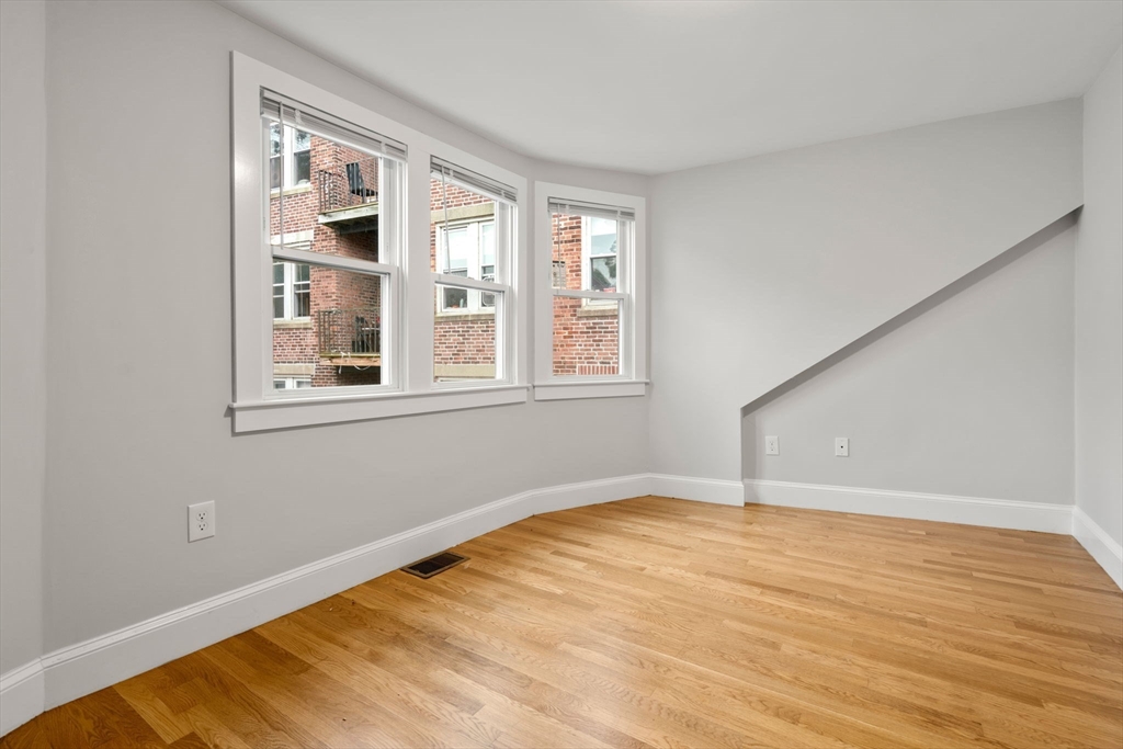 129 Sutherland Road, Unit A Boston, MA 02135 - Photo 28 of 38 a view of an empty room with wooden floor and a window