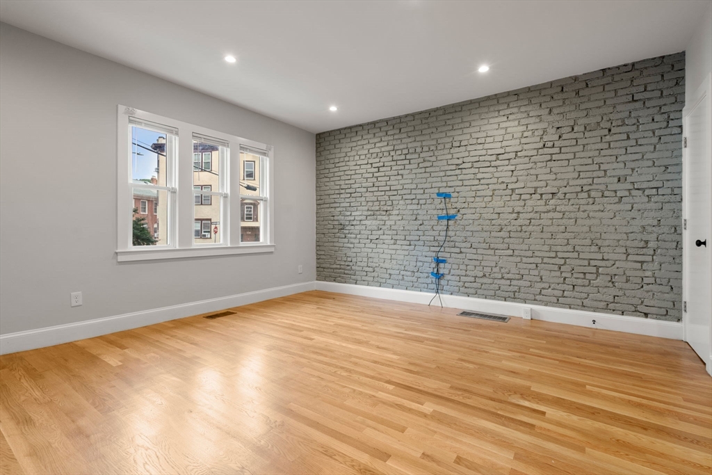 129 Sutherland Road, Unit A Boston, MA 02135 - Photo 3 of 38 a view of empty room with wooden floor and fan