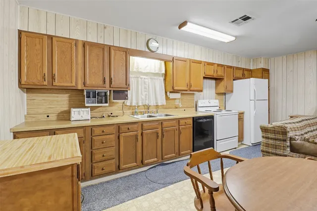 a kitchen a sink a window and chairs