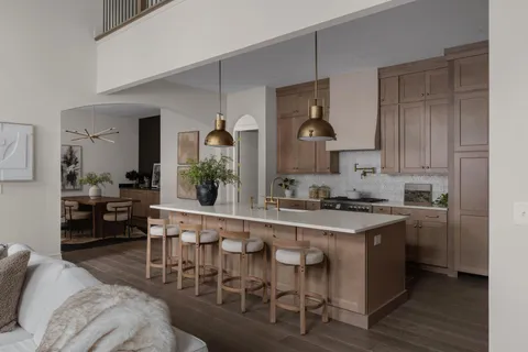 a large white kitchen with granite countertop a stove a sink a dining table and chairs