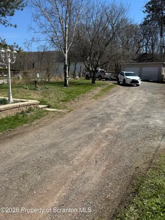 a view of a yard with a house and trees in the background